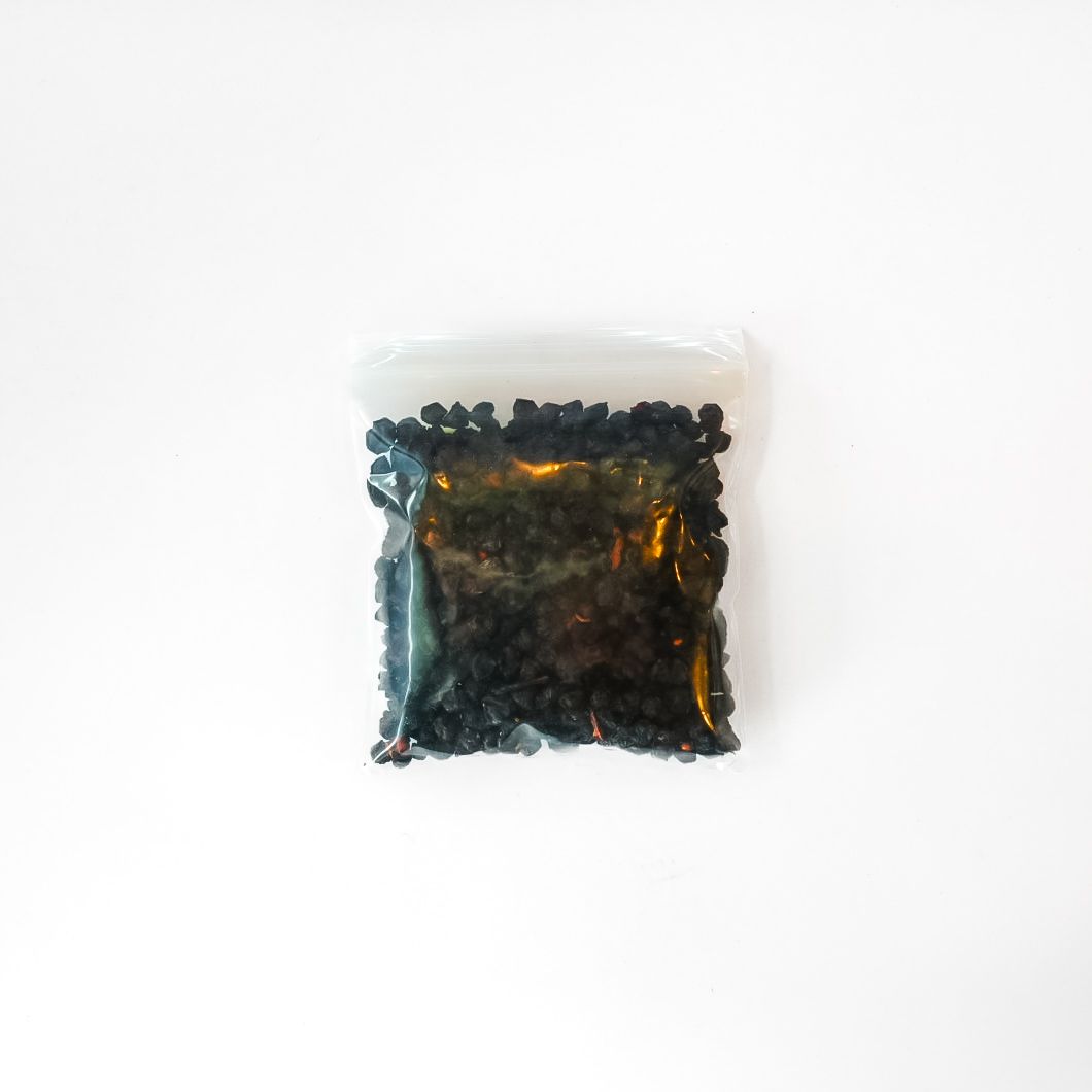 Clear plastic bag of dried schisandra berries with a bright yellow label on a white background