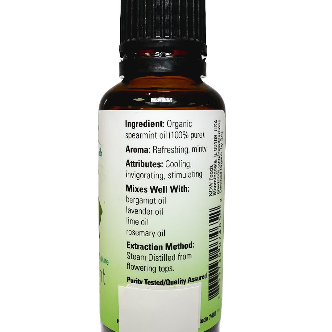 NOW peppermint essential oil bottle with green label and black cap on a white background