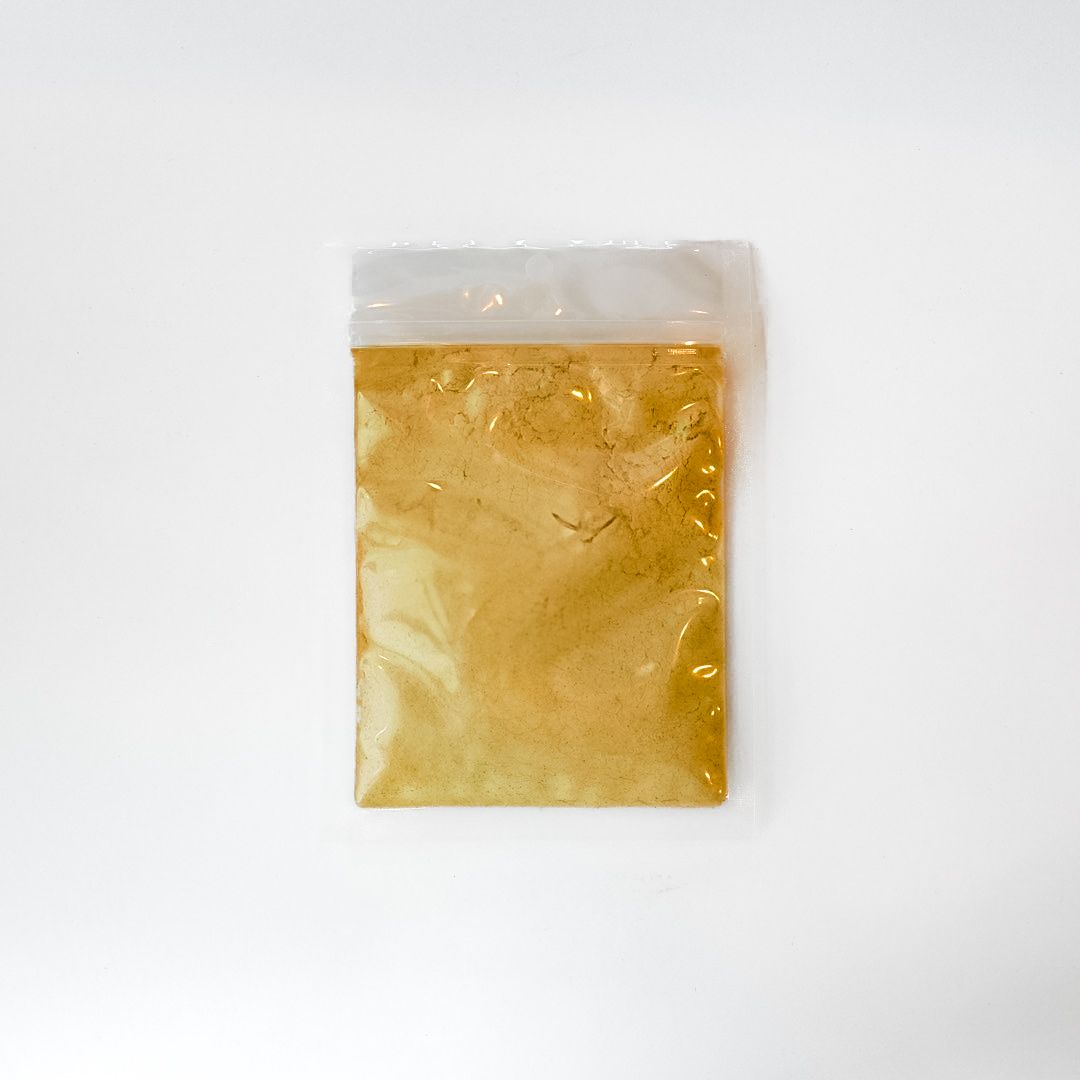 Small clear plastic bag of brownish powder with a bright yellow label on a white background