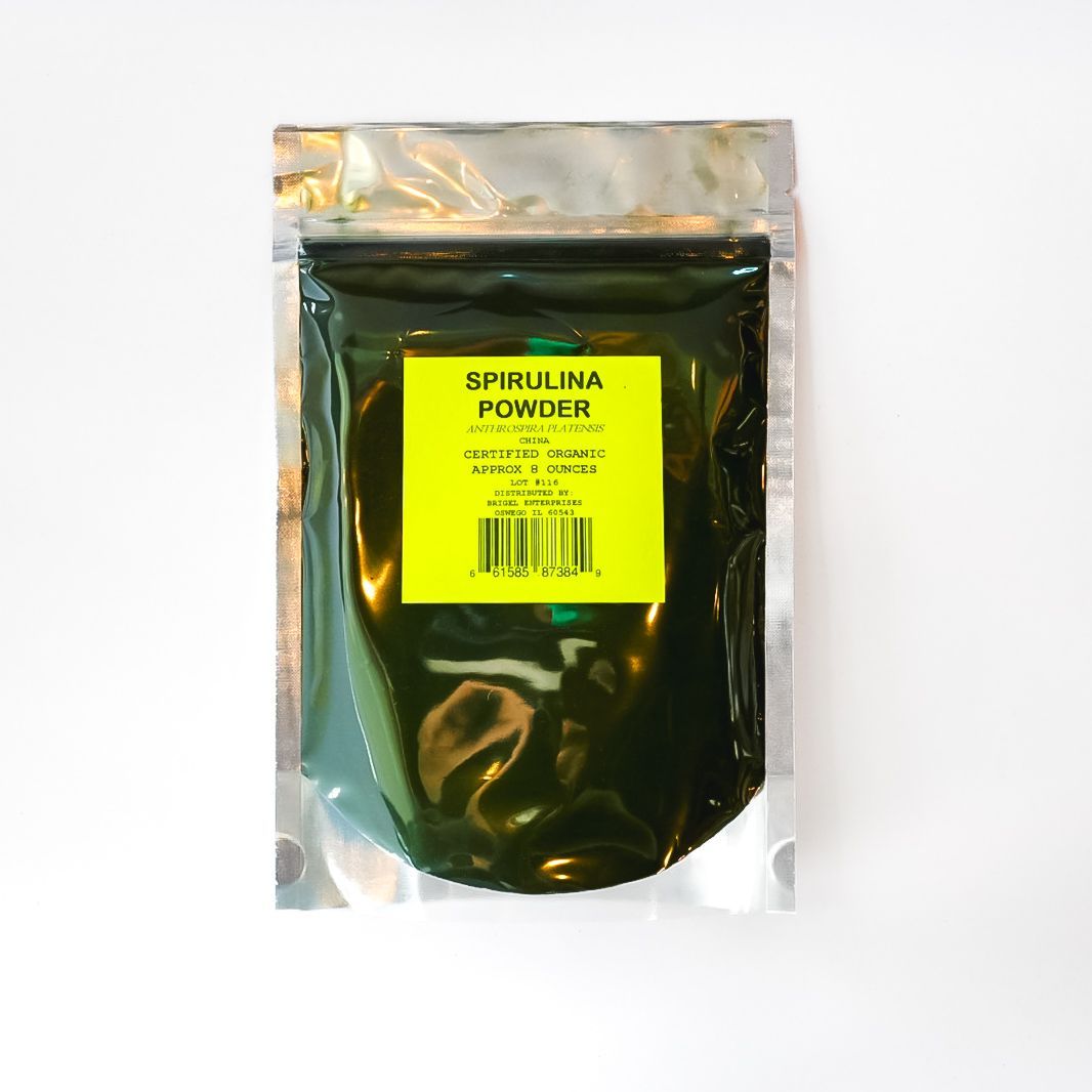 Sealed pouch of dark green spirulina powder with a bright yellow label