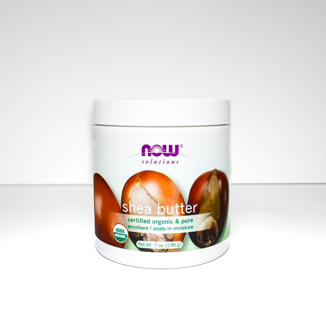 White jar of shea butter cream with purple label on a plain light background