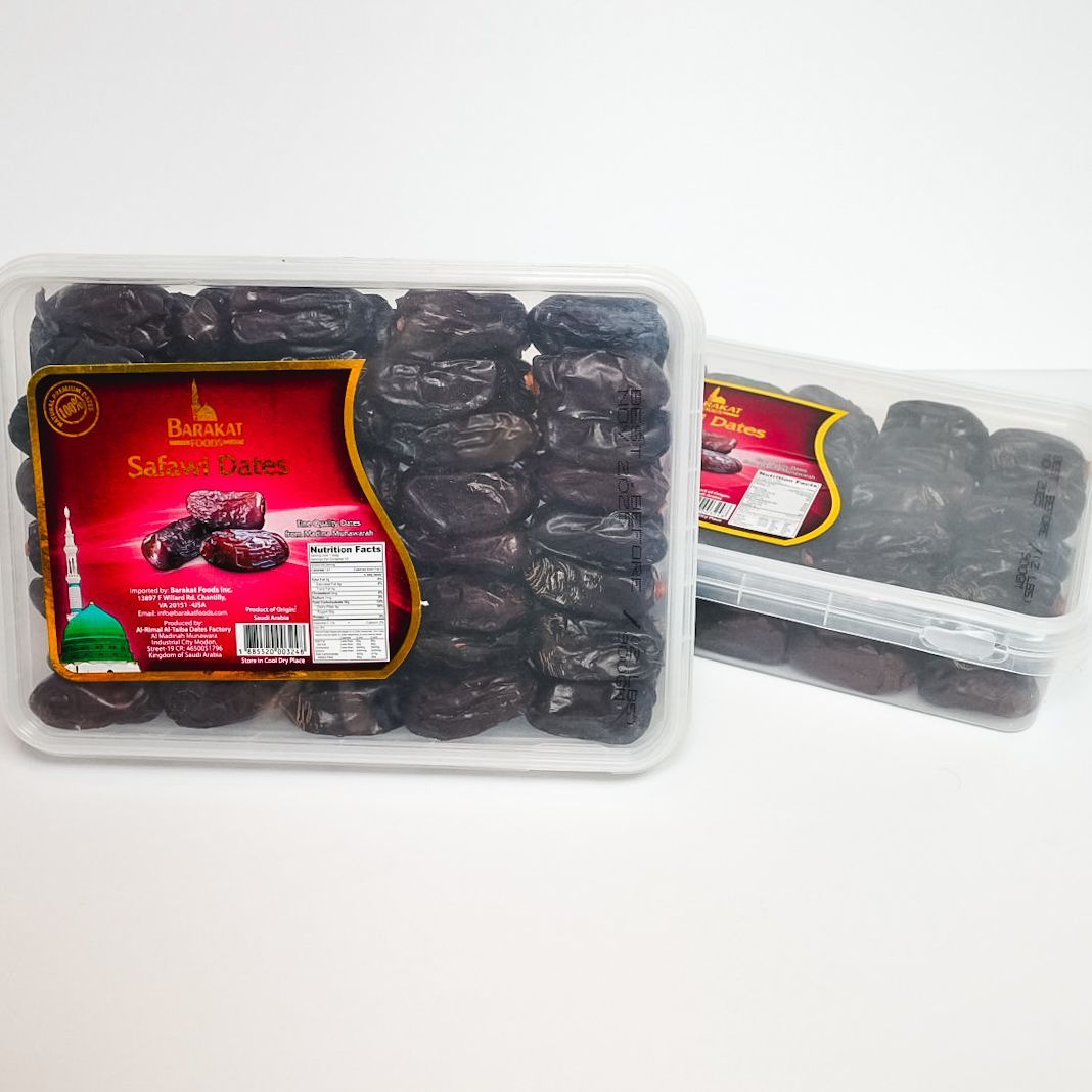 Two clear trays of dark dried dates with red labels on a white background