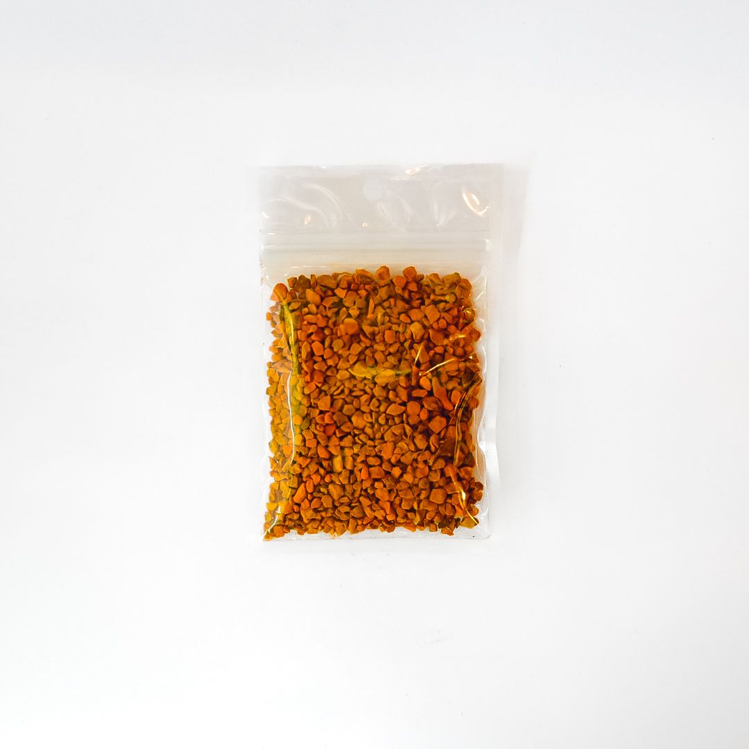 Small clear plastic bag of orange dried root with a bright yellow label and barcode on a white background