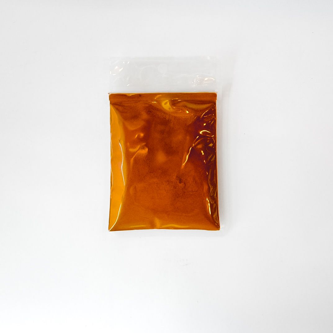 Orange and yellow pouch labeled “TURMERIC ROOT POWDER” on a white background