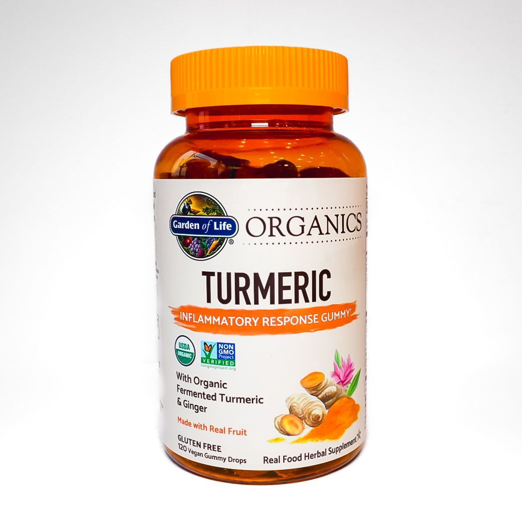 Orange bottle of turmeric supplement with white label and orange cap on a white background