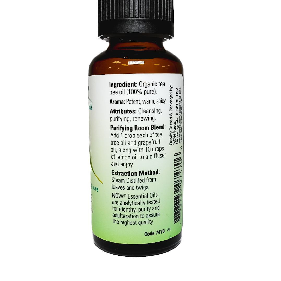 Small amber bottle of NOW tea tree essential oil with a black cap and green leaf label.