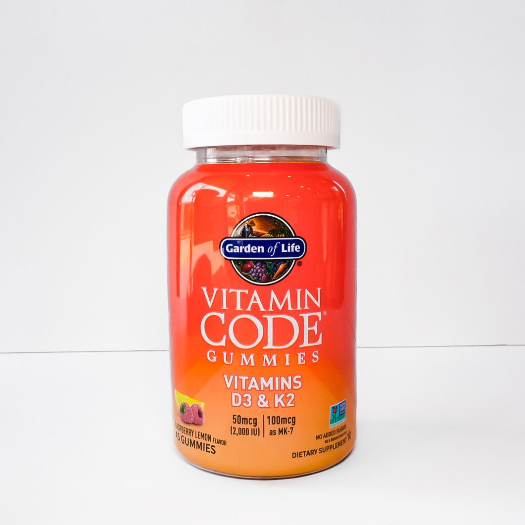 Orange vitamin supplement bottle with white cap and red label on a white background