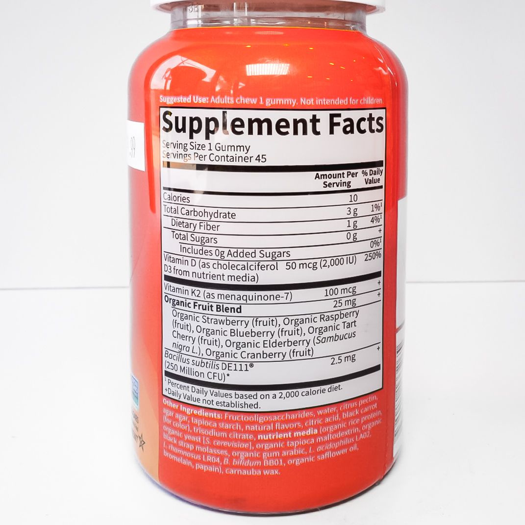 Orange vitamin supplement bottle with white cap and red label on a white background
