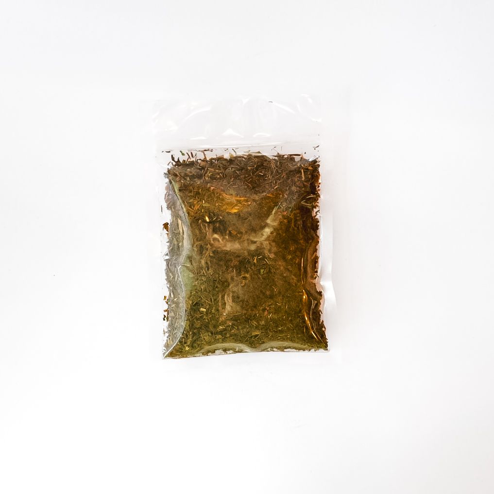 Clear plastic bag of dried herbs or tea with a bright yellow label, centered on a white background