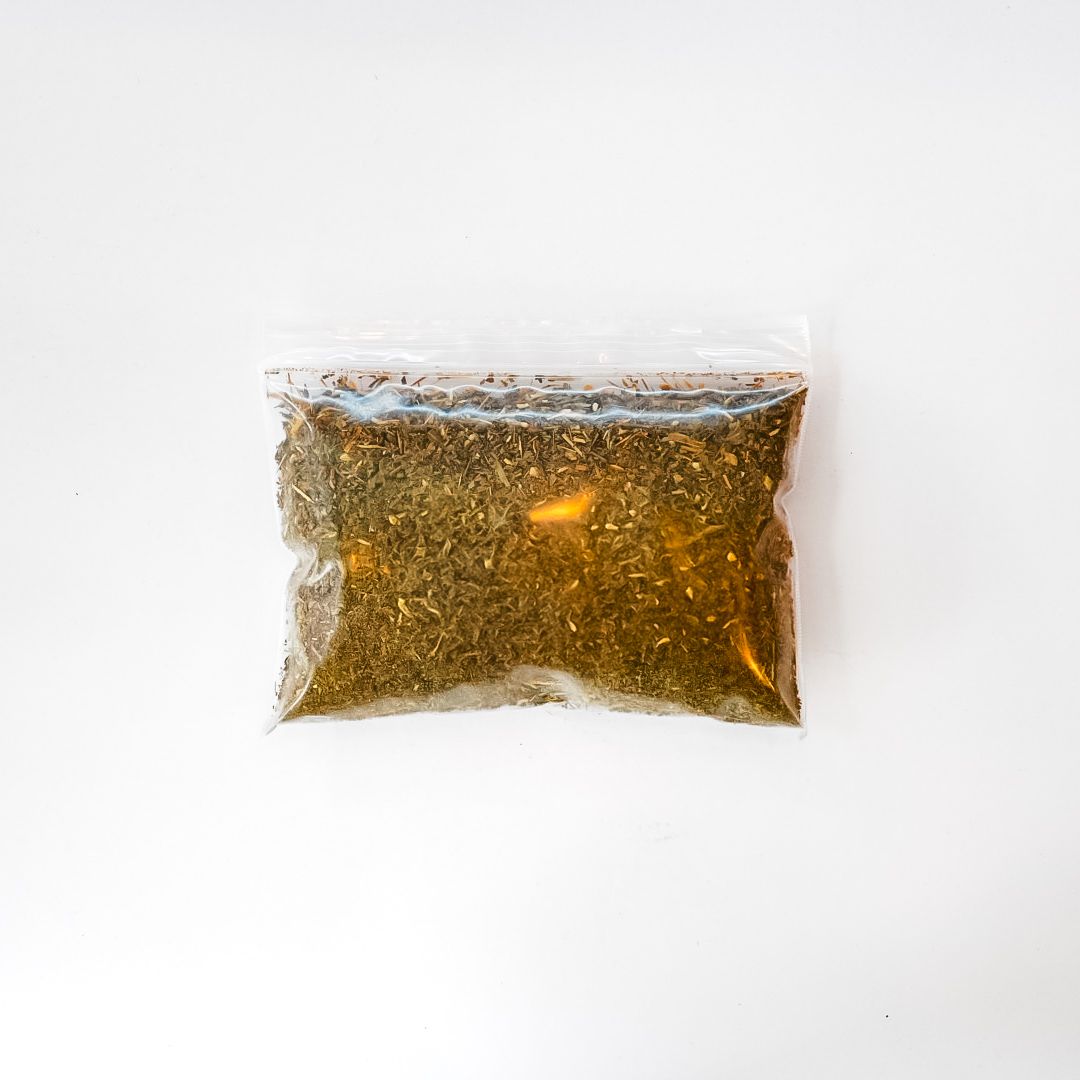 Clear plastic bag of dried herbs with a bright yellow label on a white background