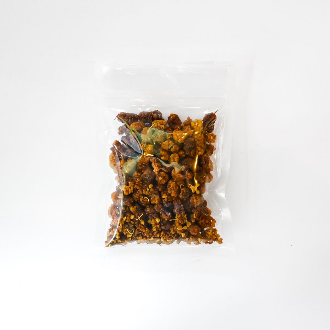 Clear plastic bag of dried white mulberries with a bright green label on a white background