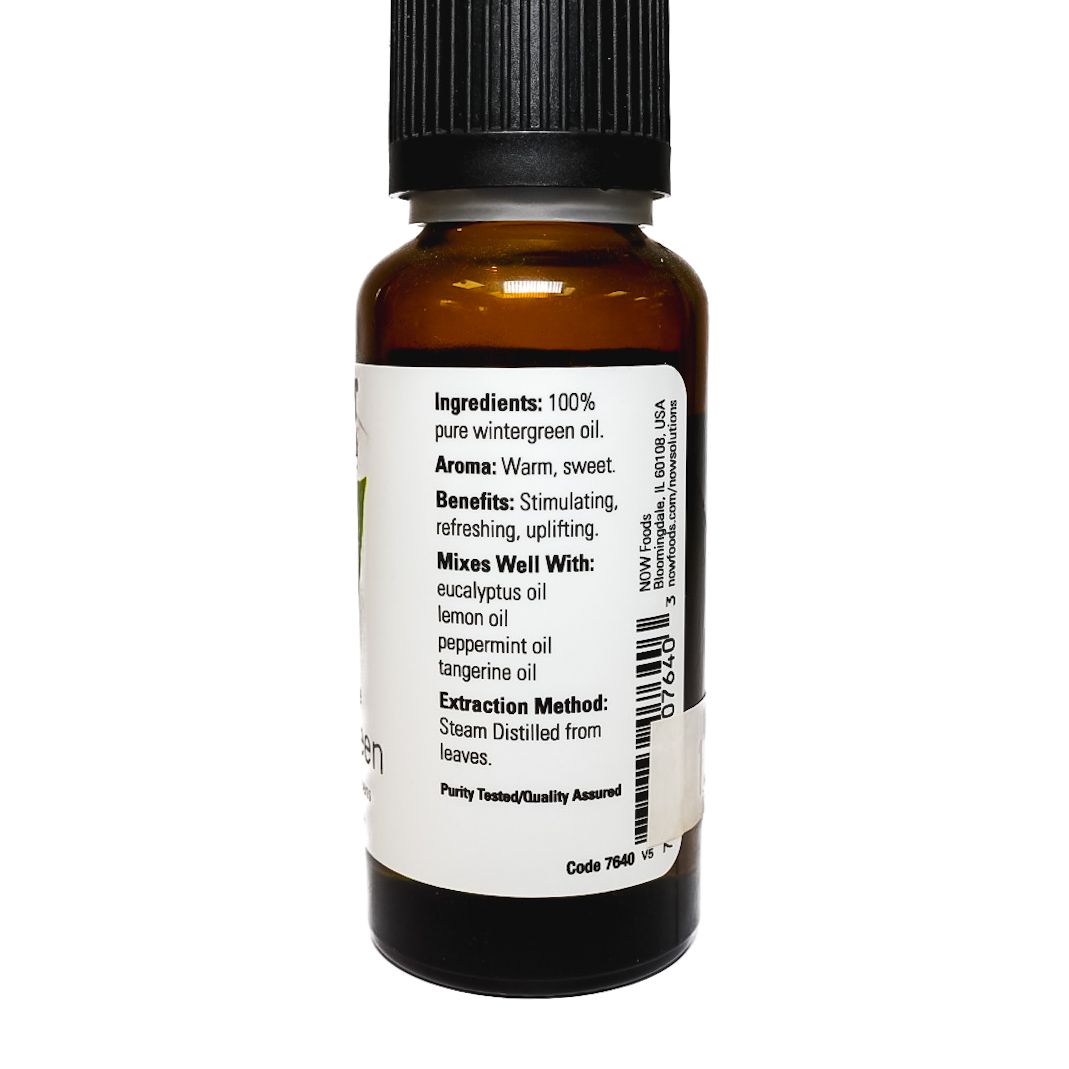 Small amber bottle of NOW Wintergreen essential oil with black cap and green leaf label on white background