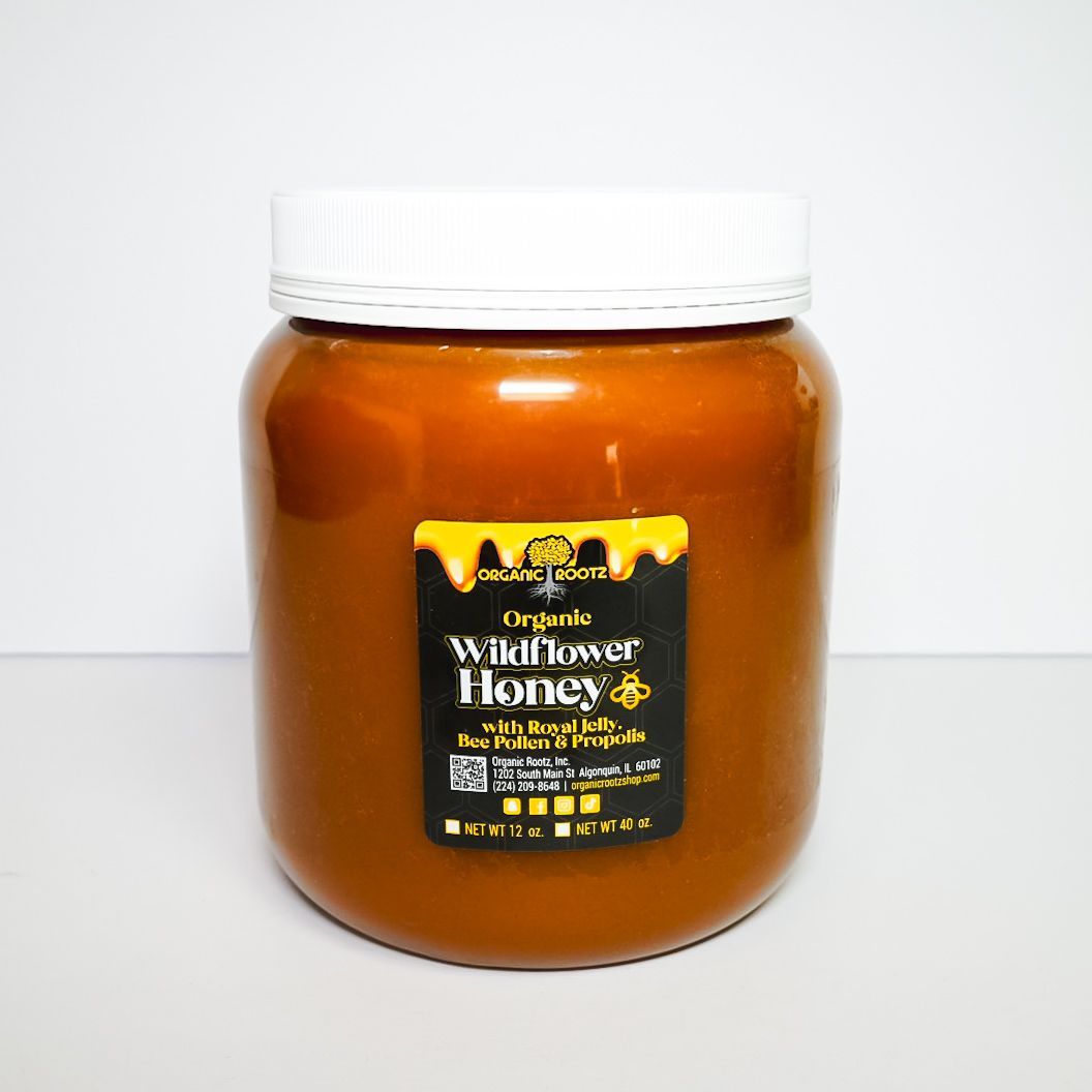 Jar of amber wildflower honey with a white lid and black label on a plain background