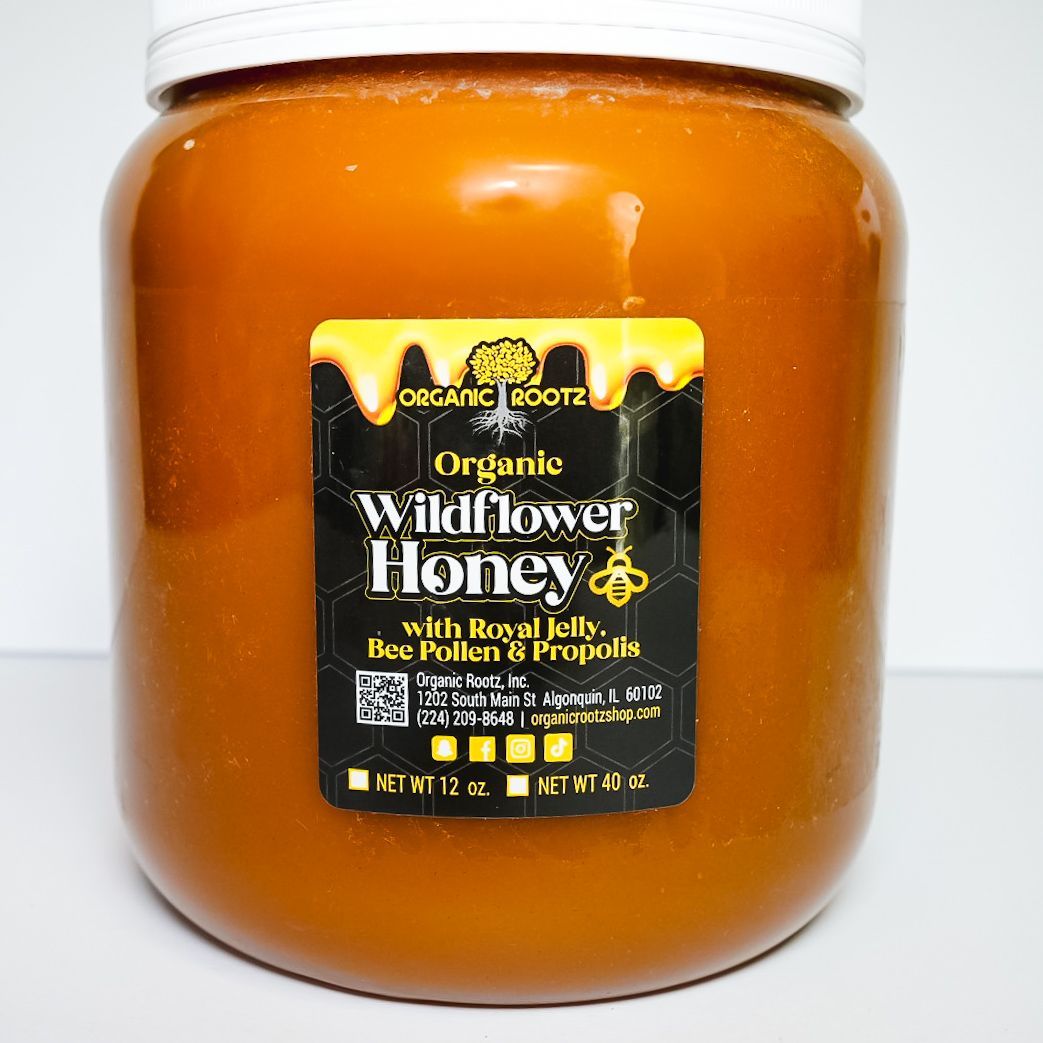 Jar of amber wildflower honey with a white lid and black label on a plain background