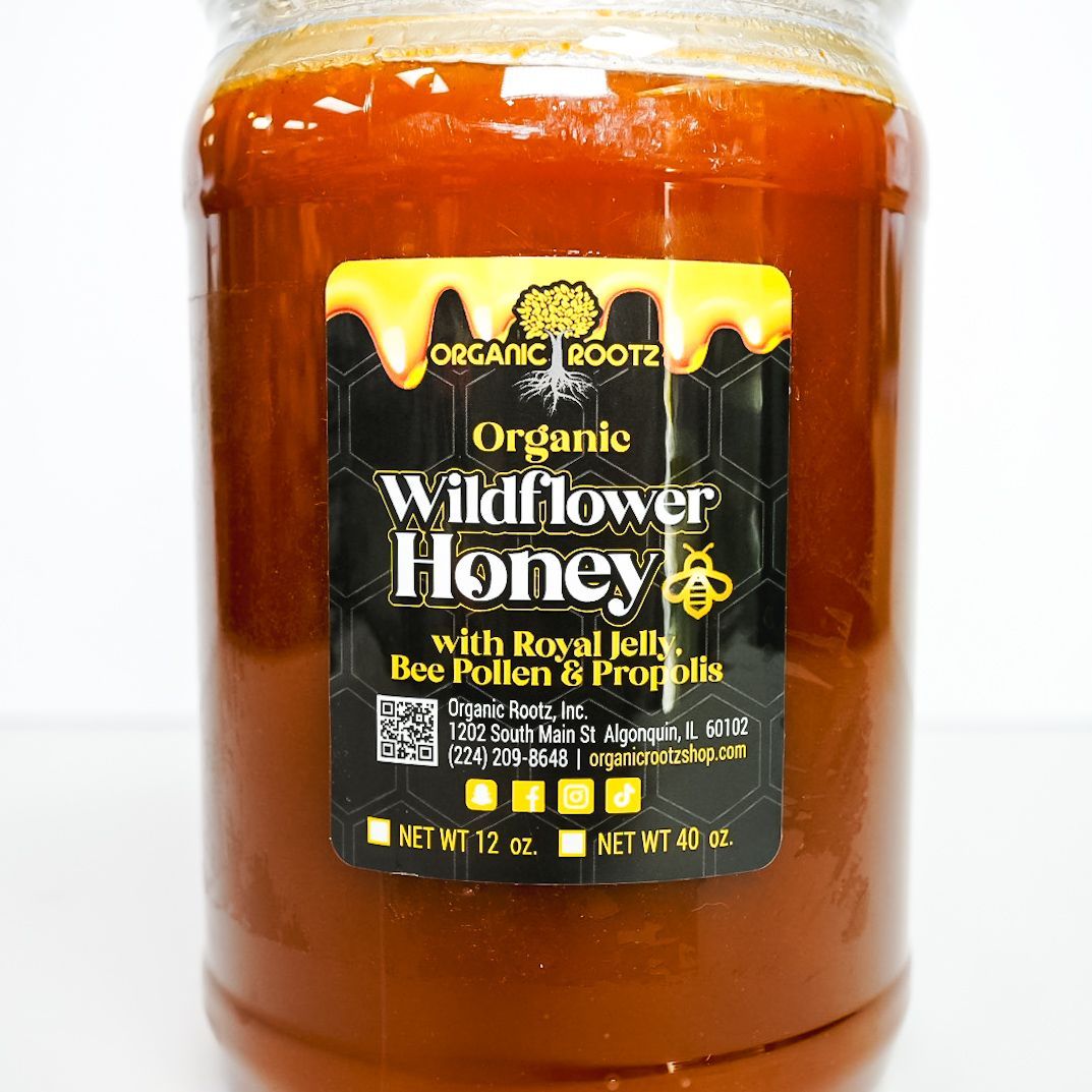 Jar of amber honey with a white lid and black label on a plain white background