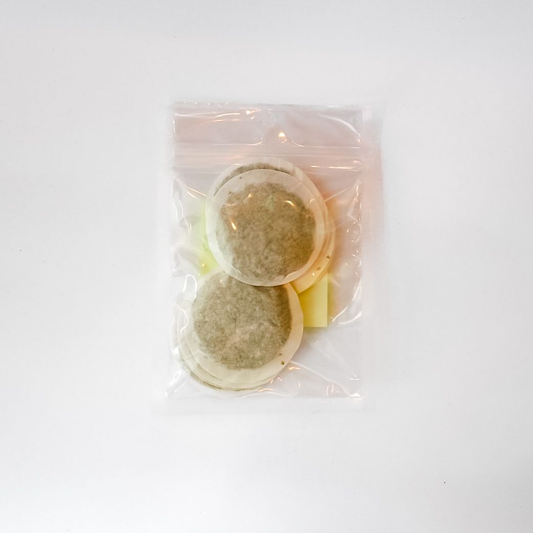 Clear plastic bag with a yellow label containing a tan round object on a white background