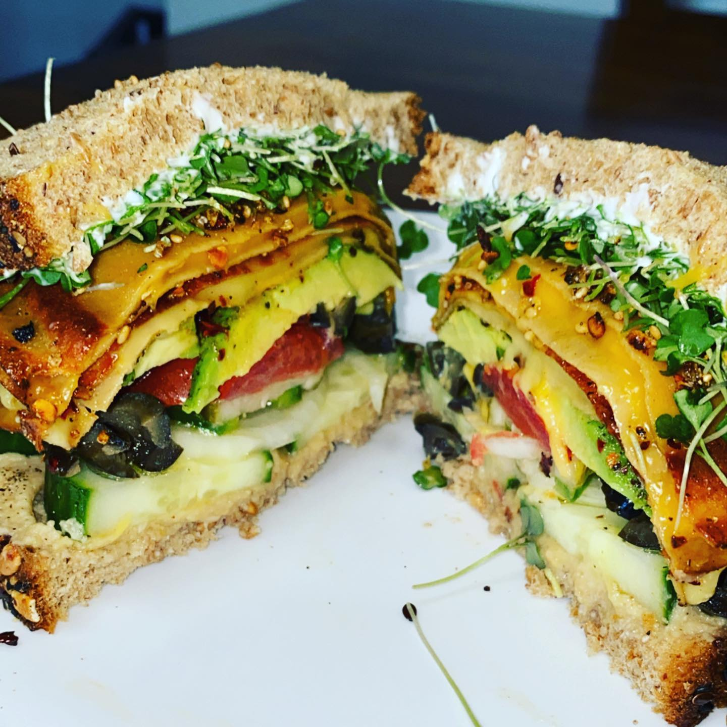 a white plate topped with a sandwich and vegetables on a green table .