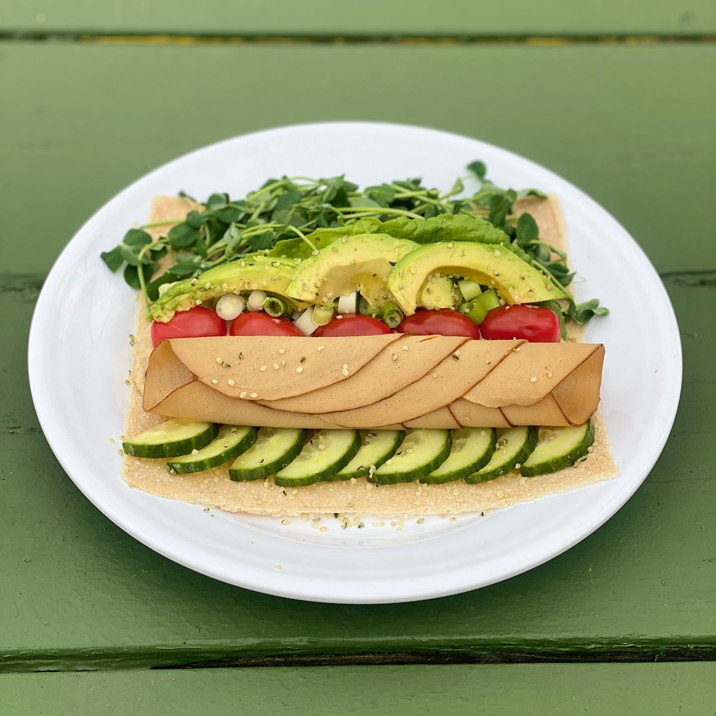A white plate topped with a sandwich and vegetables on a green table.