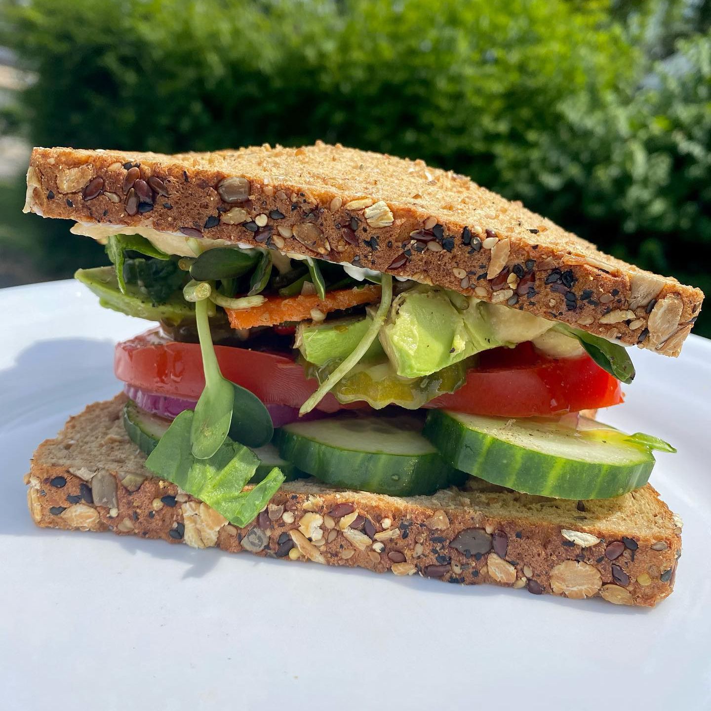 a sandwich with tomatoes , cucumbers , and lettuce on a white plate .