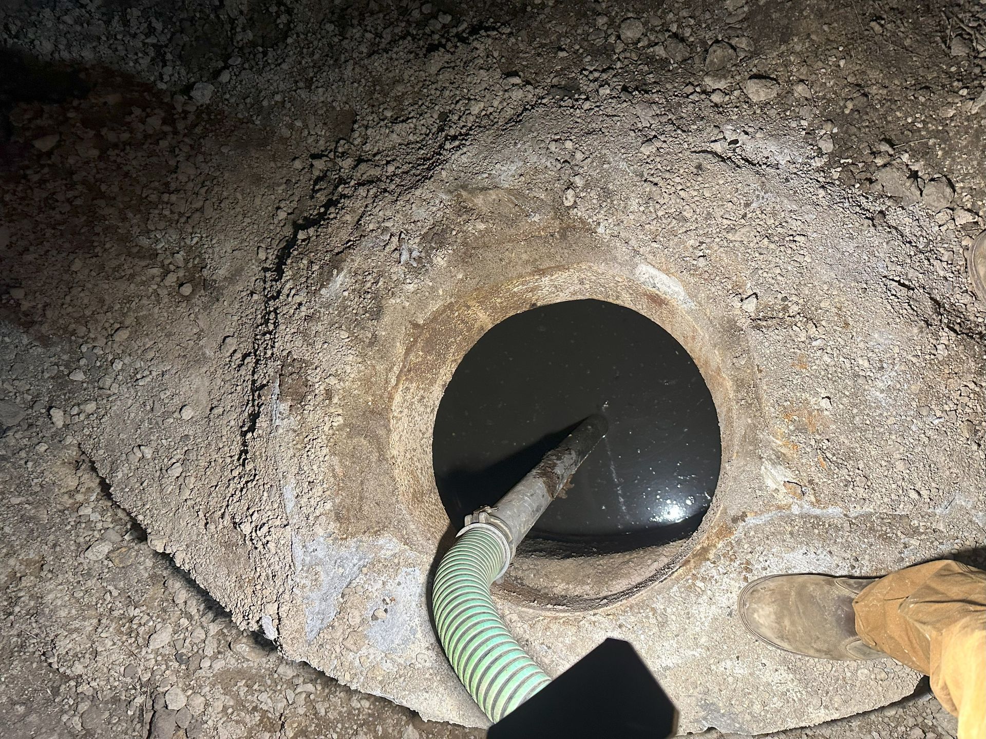 A person is pumping water into a hole in the ground.