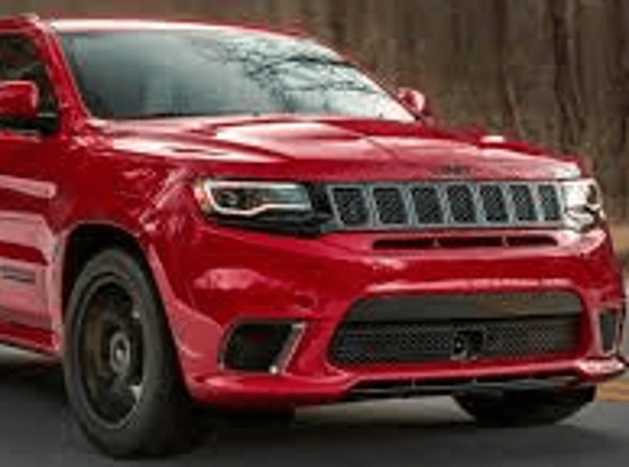 Red SUV on a road, front view, with black grille and wheels against a wooded background