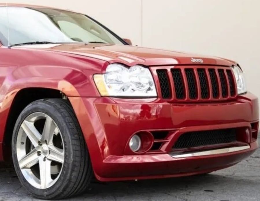 Red SUV parked outdoors, front view with silver grille and wheels.