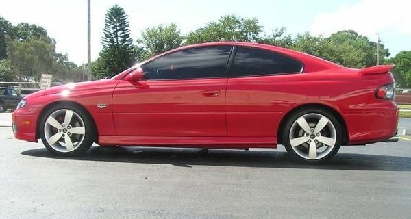 Red sports coupe parked outdoors on a sunny day, side view