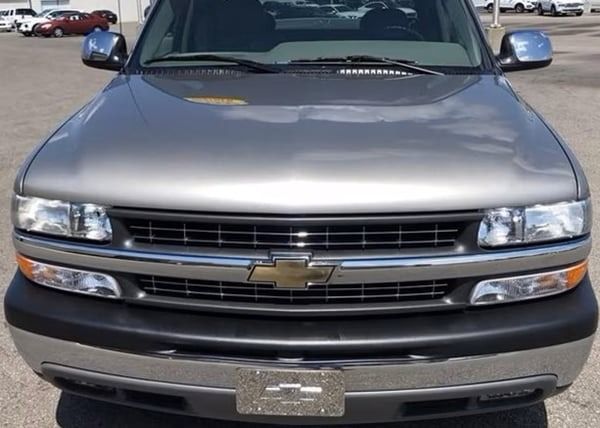 Front view of a silver Chevrolet SUV parked in a lot, with a black grille and gold emblem.