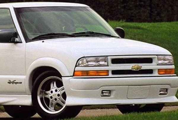 White Chevrolet pickup truck angled front view on a road, with chrome grille and wheels.
