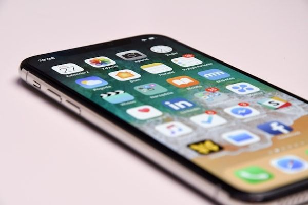 Smartphone lying on a pink surface, showing a grid of colorful app icons.