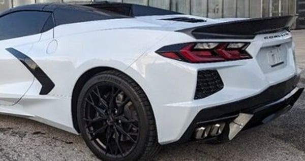White sports car with black roof and rims, rear three-quarter view parked outdoors.