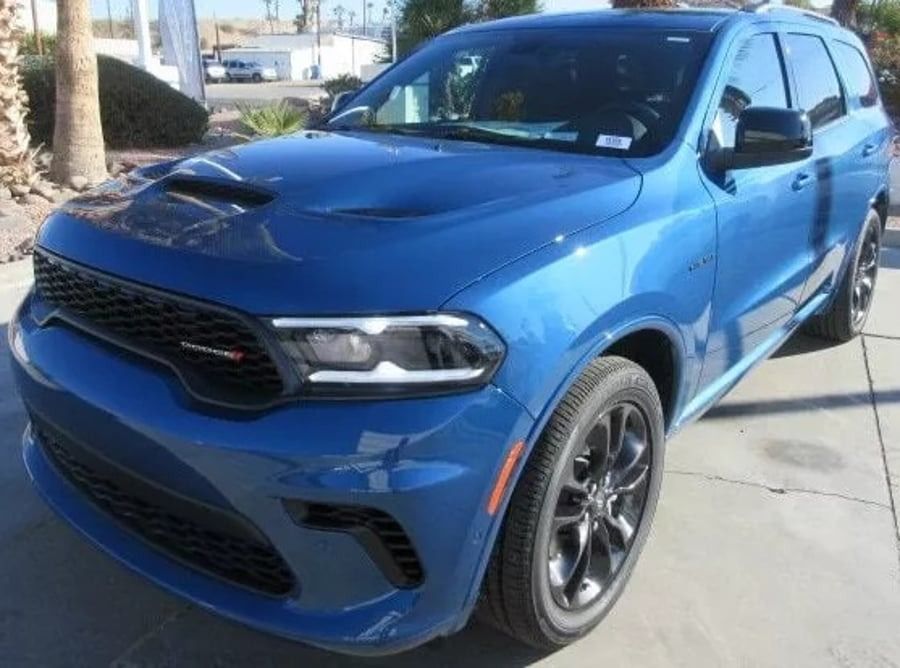 Blue SUV parked outdoors in sunlight, front three-quarter view.