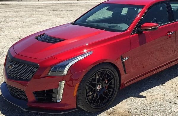 Red sports sedan with black wheels parked on a sunny lot