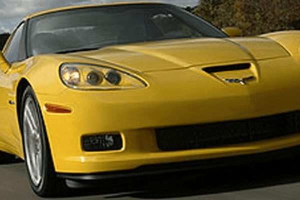 Yellow sports car angled front view on a road, with a sleek hood and black grille.