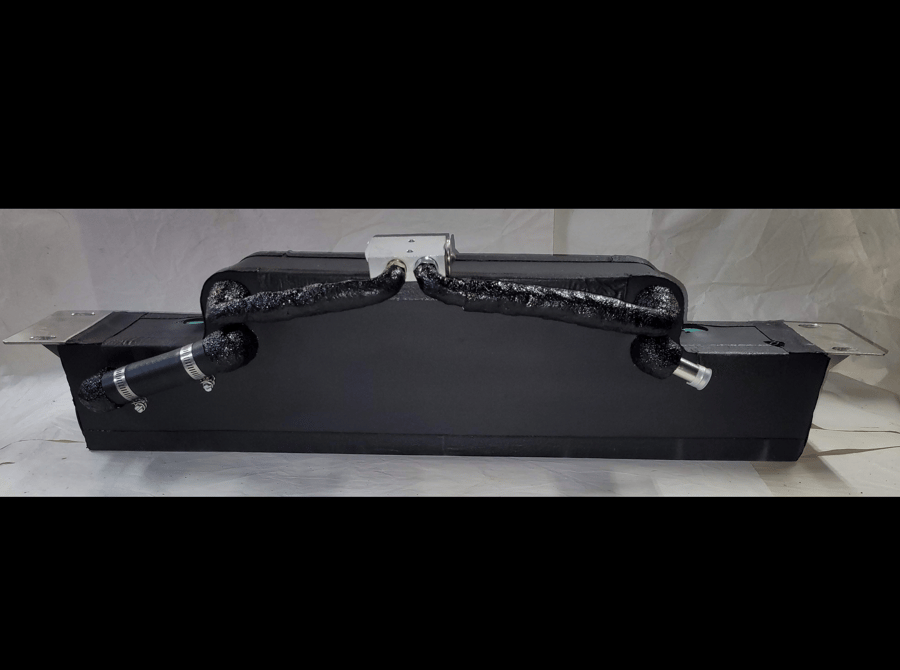Black duffel bag with silver zippers and strap, resting on a black box against a gray backdrop