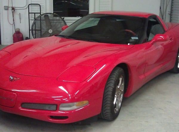 Red sports car parked indoors in a garage, front view.