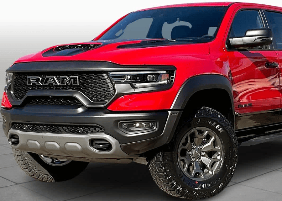 Red RAM pickup truck with black grille and off-road tires, parked outdoors.