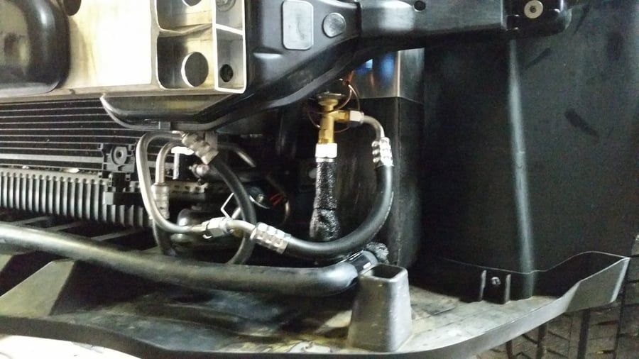 Close-up of engine bay wiring and hoses near a black plastic air intake housing.