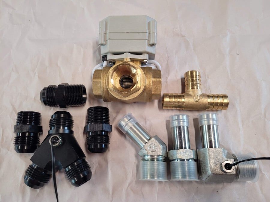 Assorted metal and plastic pipe fittings and valve adapters laid out on a light background