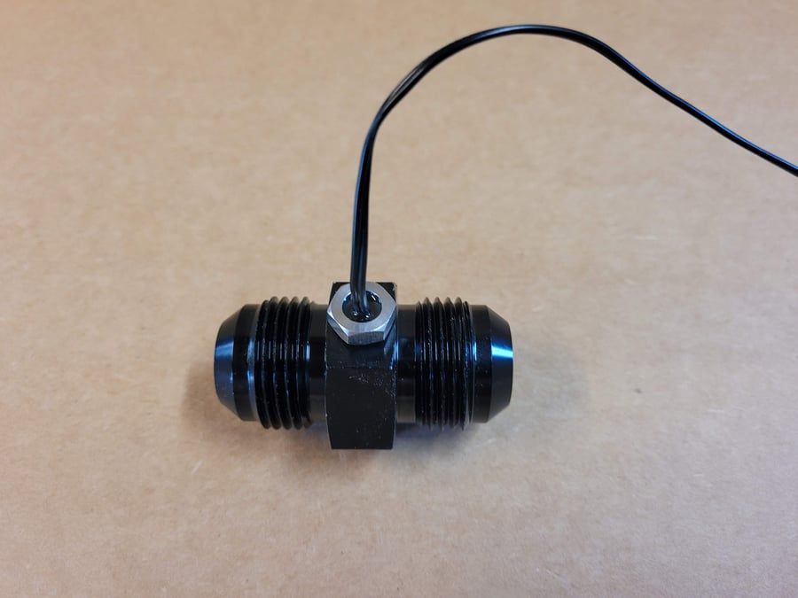 Black cable connector with a wire attached, lying on a tan surface