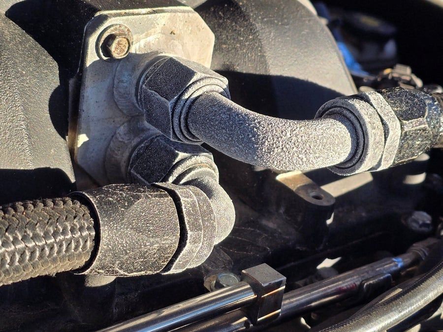 Close-up of black rubber hoses and fittings connected to a metal engine component.
