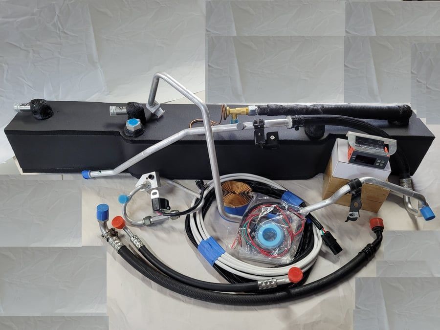 Lab bench setup with a black rectangular tank, clear tubing, wires, and a circular component on a white surface