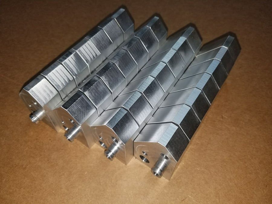 Four shiny metal mechanical parts aligned on a brown surface
