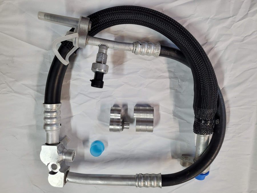 Black braided hose assembly with silver metal fittings and two small couplers on a white cloth background