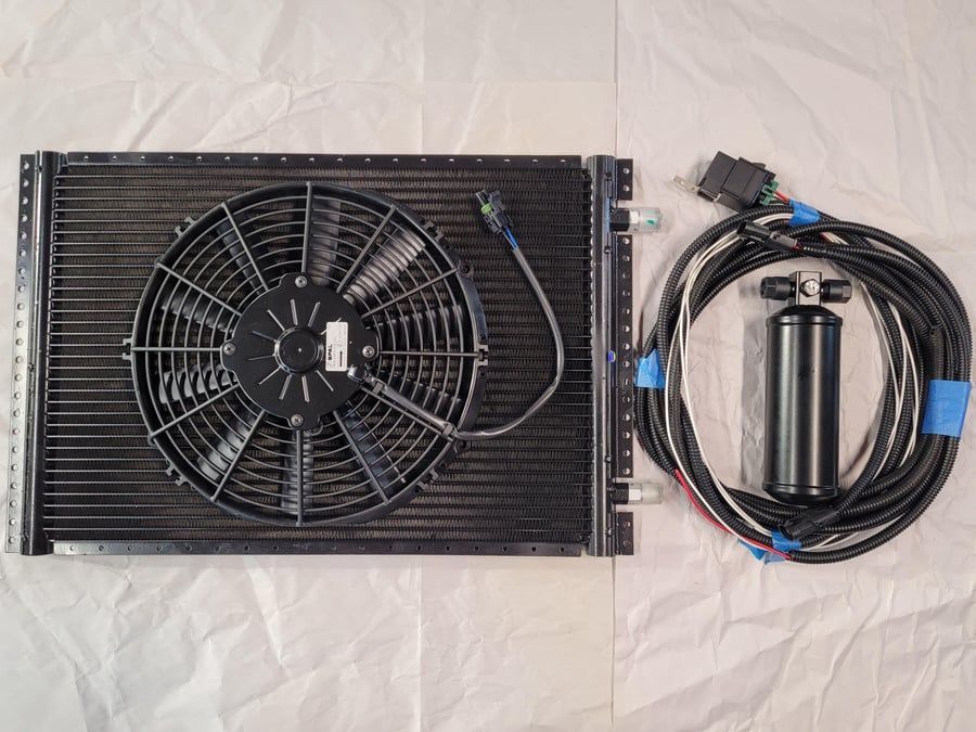 Black fan-cooled automotive part beside coiled wiring harness on a light background
