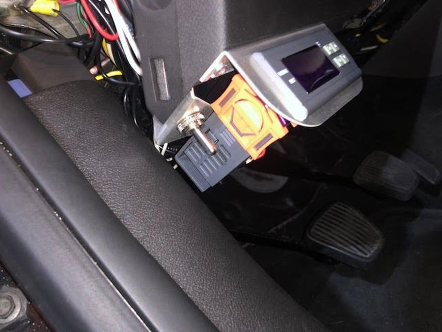 Close-up of a car steering column with an ignition lock and a key inserted.