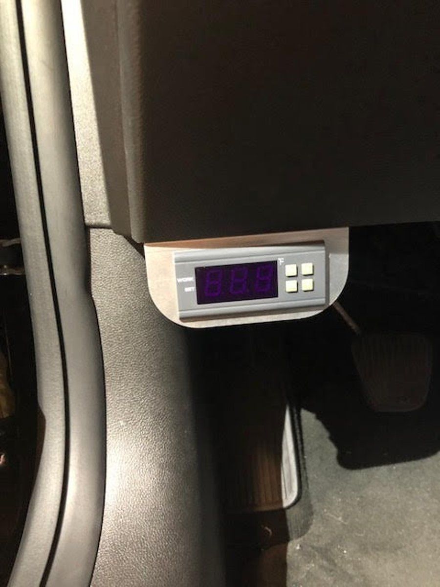 Car ceiling console with a small purple display and buttons, mounted above the front seats