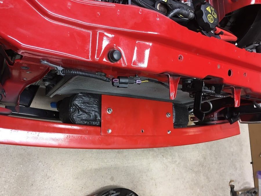 Red vehicle undercarriage with exposed mechanical parts and a red protective panel.