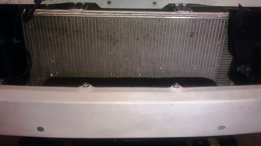 Close-up of a car front grille and bumper with a silver mesh intercooler visible behind it.