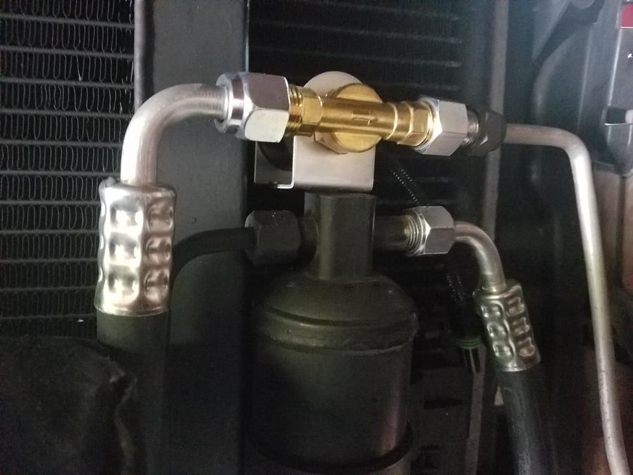Close-up of metal pipes and brass valve assembly on a black mechanical unit